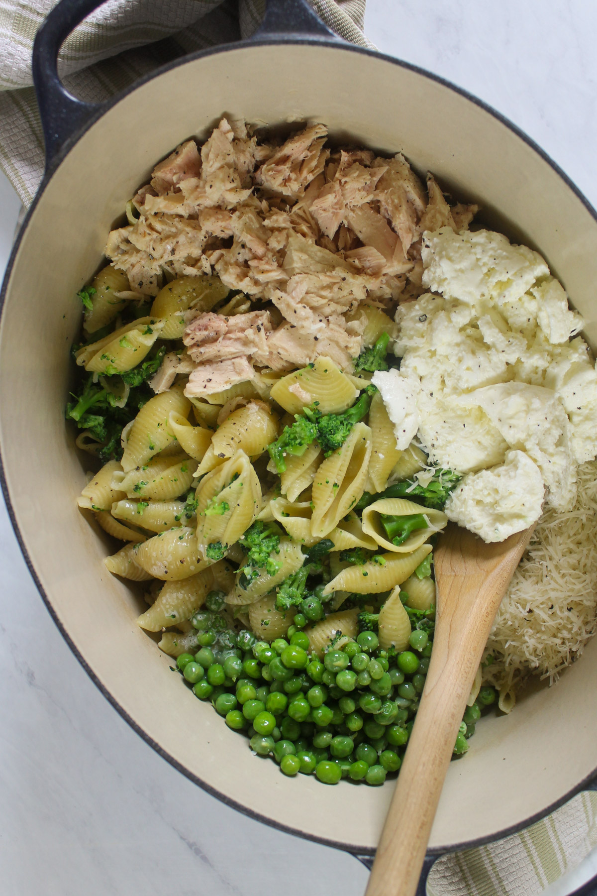 Adding tuna, cheese and cream to the drained pasta and broccoli.