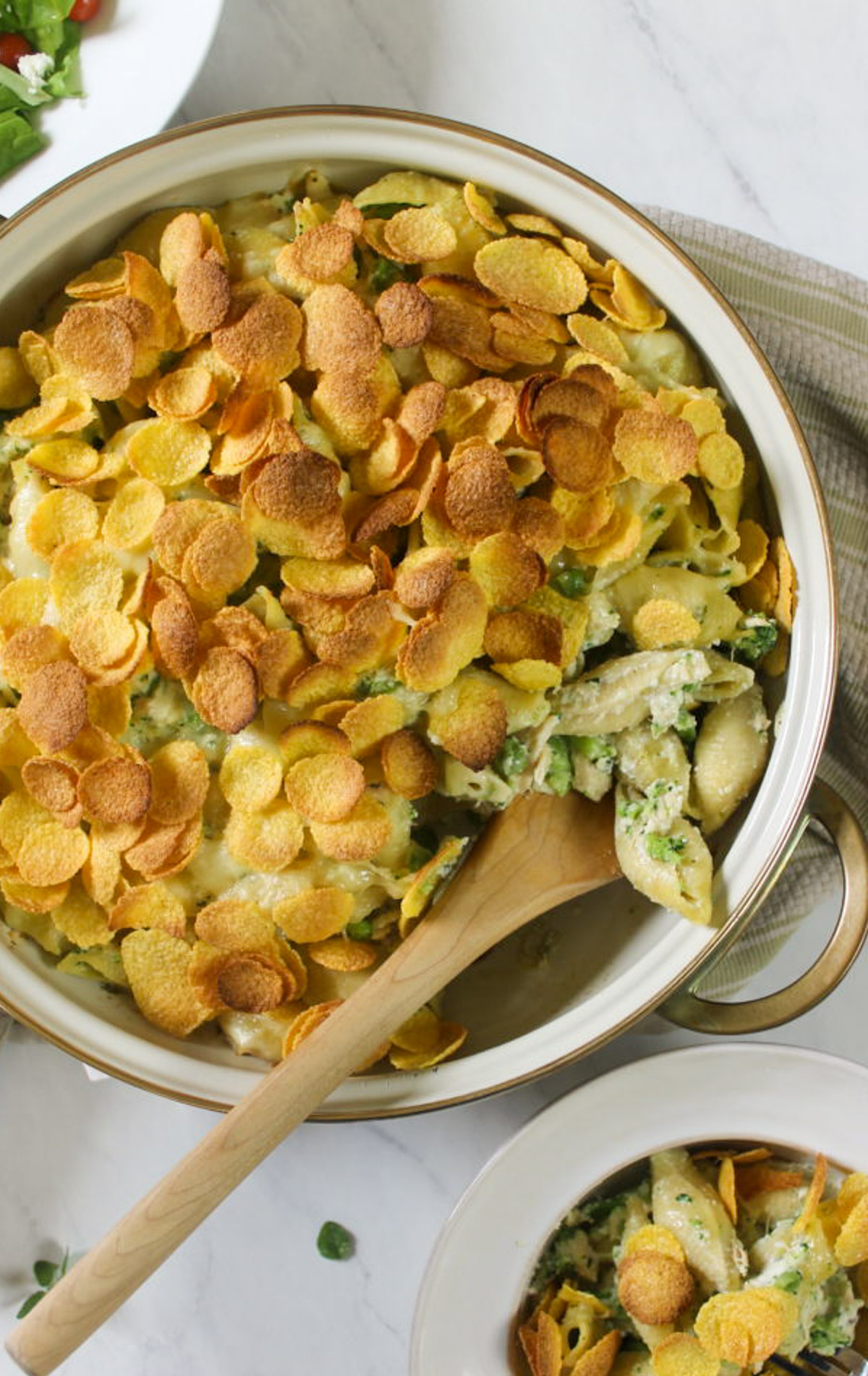 Tuna Broccoli Pasta Bake in a round baking dish with a wooden spoon for serving.