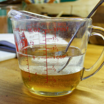 A glass measuring cup of honey and coconut oil for granola.