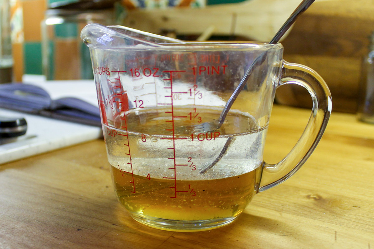 A glass measuring cup of honey and coconut oil for granola.