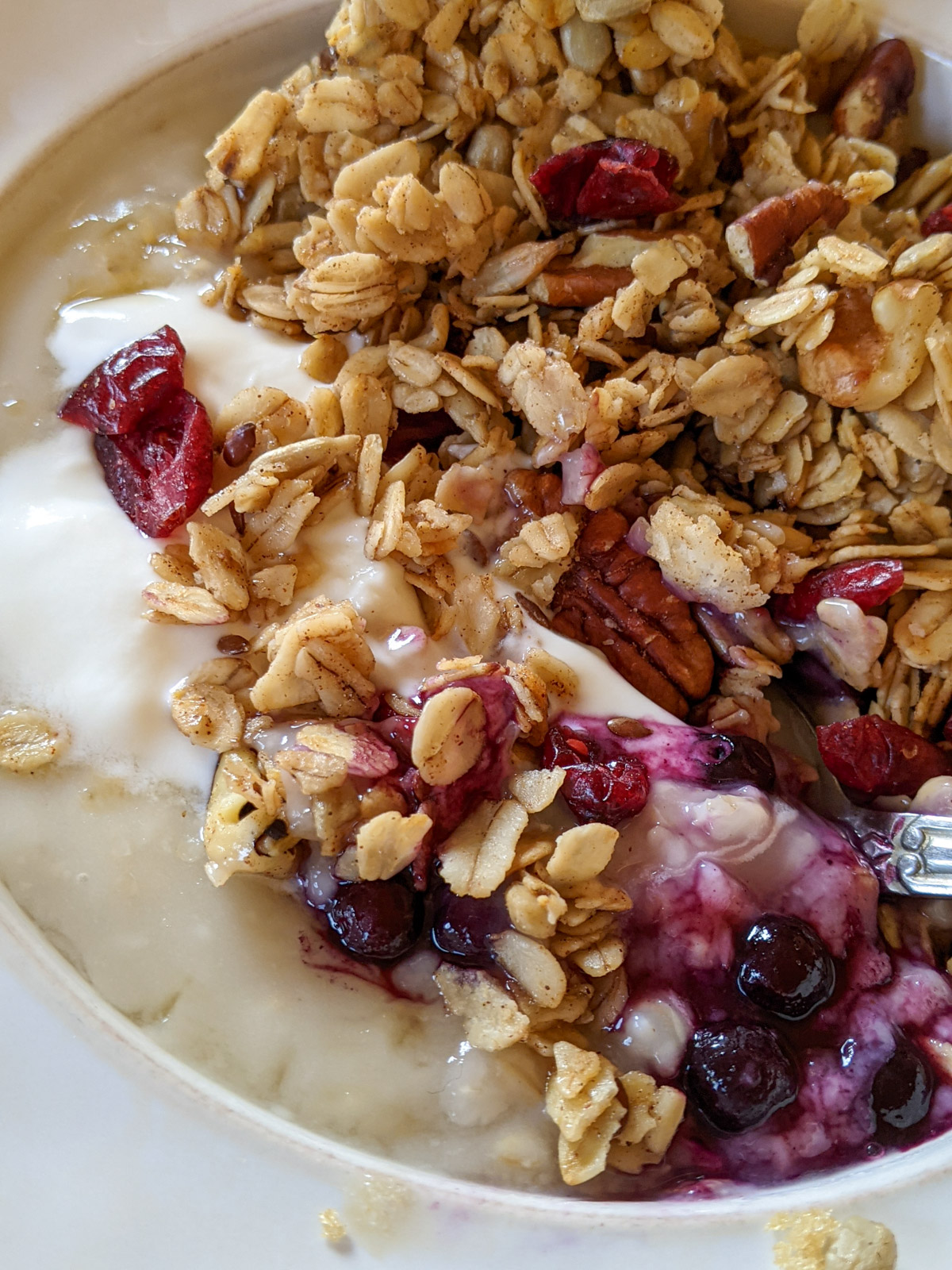 A bowl of oatmeal with blueberries and yogurt topped with homemade granola.