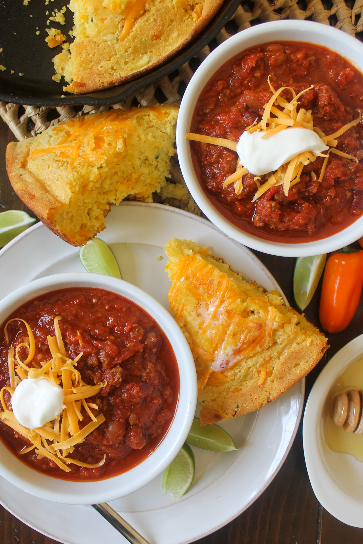 Bowls of chili on plates with wedges of cornbread.