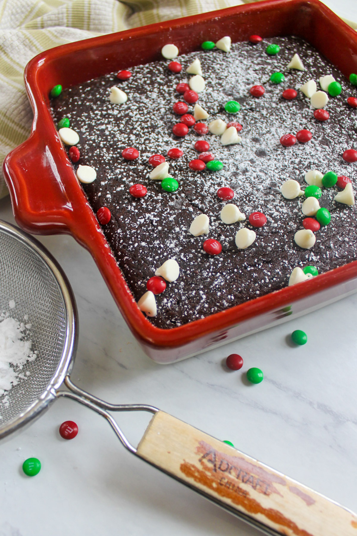 A red pan of black bean brownies topped with red and green M&M's and white chocolate chips for Christmas.