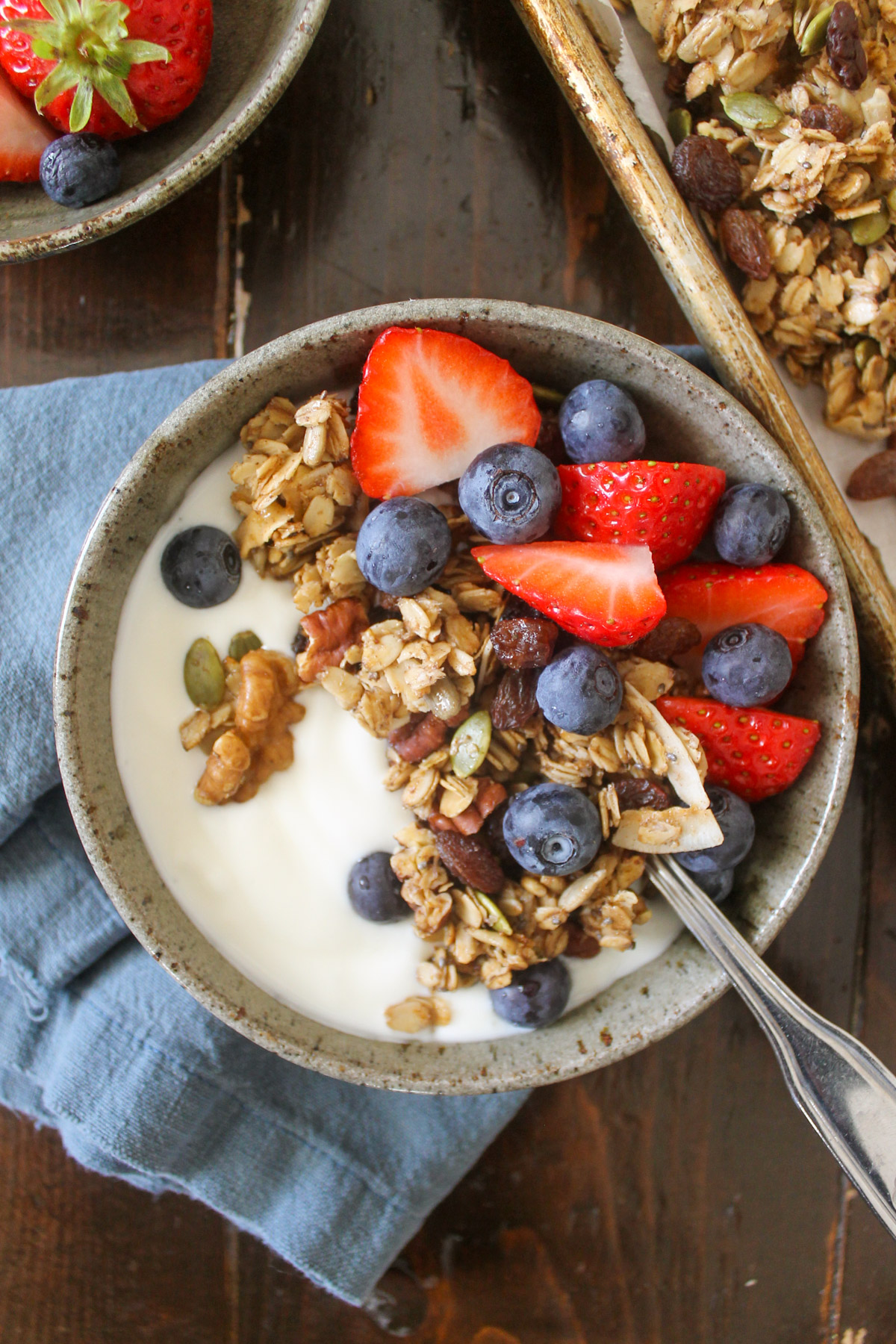 A bowl of yogurt with homemade granola, strawberries and blueberries.