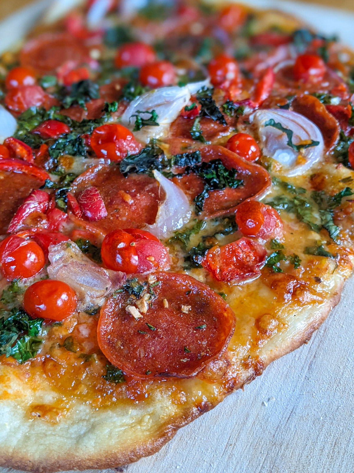 Homemade pizza with pepperoni, red cherry tomatoes, onion and herbs.