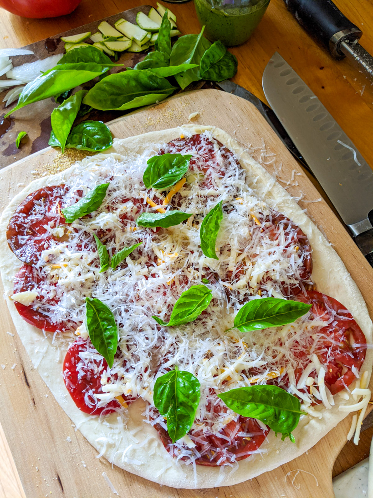 Caprese pizza before it is baked, with garden tomato, mozzarella and basil.