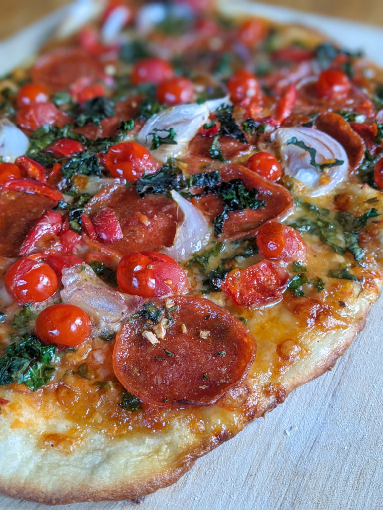 Scratch made pizza with tomato, onion, pepperoni and herbs