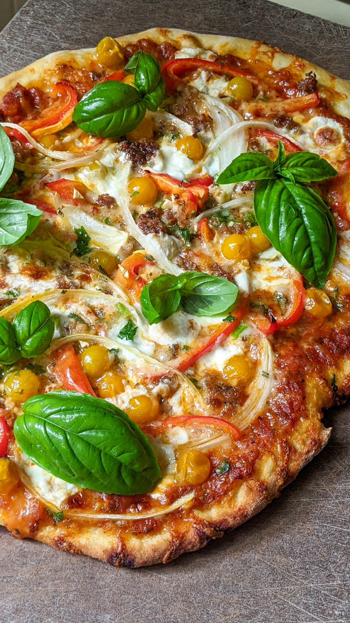 Scratch made pizza with tomato, bell pepper, sausage and basil.