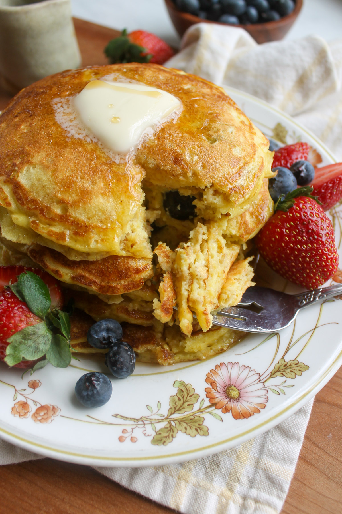 A stack of pancakes with a wedge cut out with a fork.