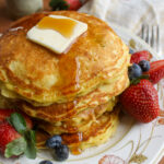 Blueberry protein pancakes on a plate with a pat of butter and syrup.