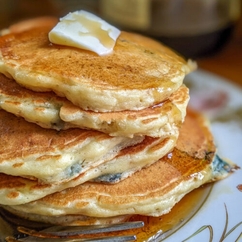 Blueberry protein pancakes on a plate with a pat of butter and syrup.