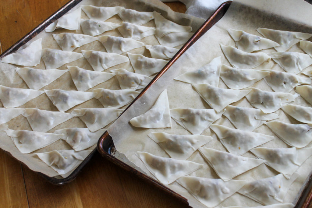 Baking sheet of homemade potstickers ready to cook or freeze.