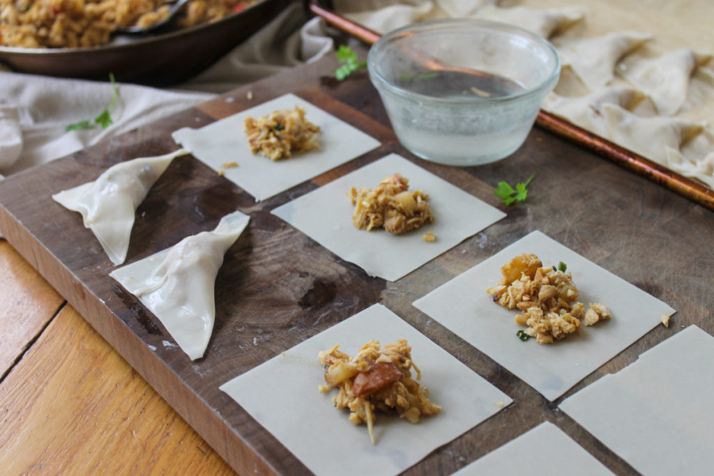 Making homemade chicken apple potstickers, adding filling.