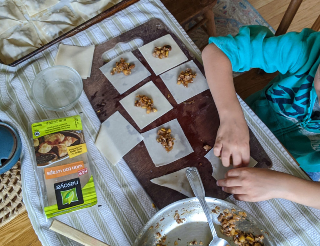 Child filling and making homemade potstickers.