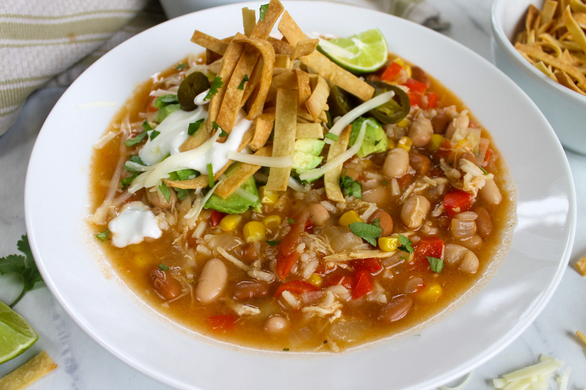 Bowl of 30 minute chicken tortilla soup with crispy corn tortilla strips.