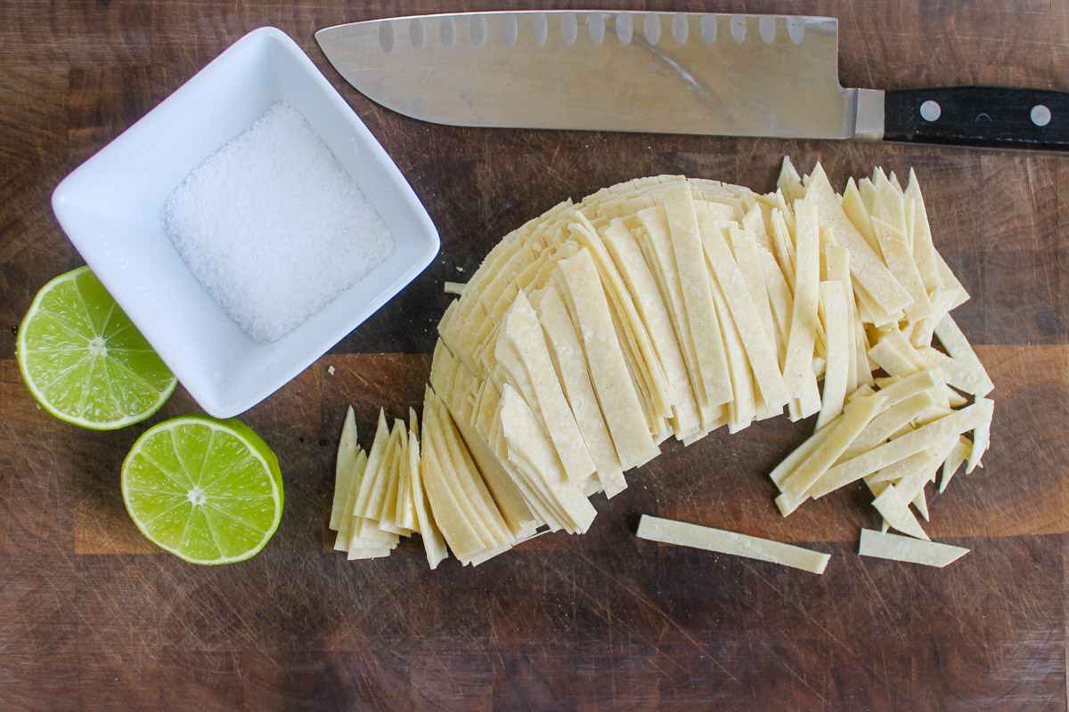 Making homemade salty lime corn tortilla strips.