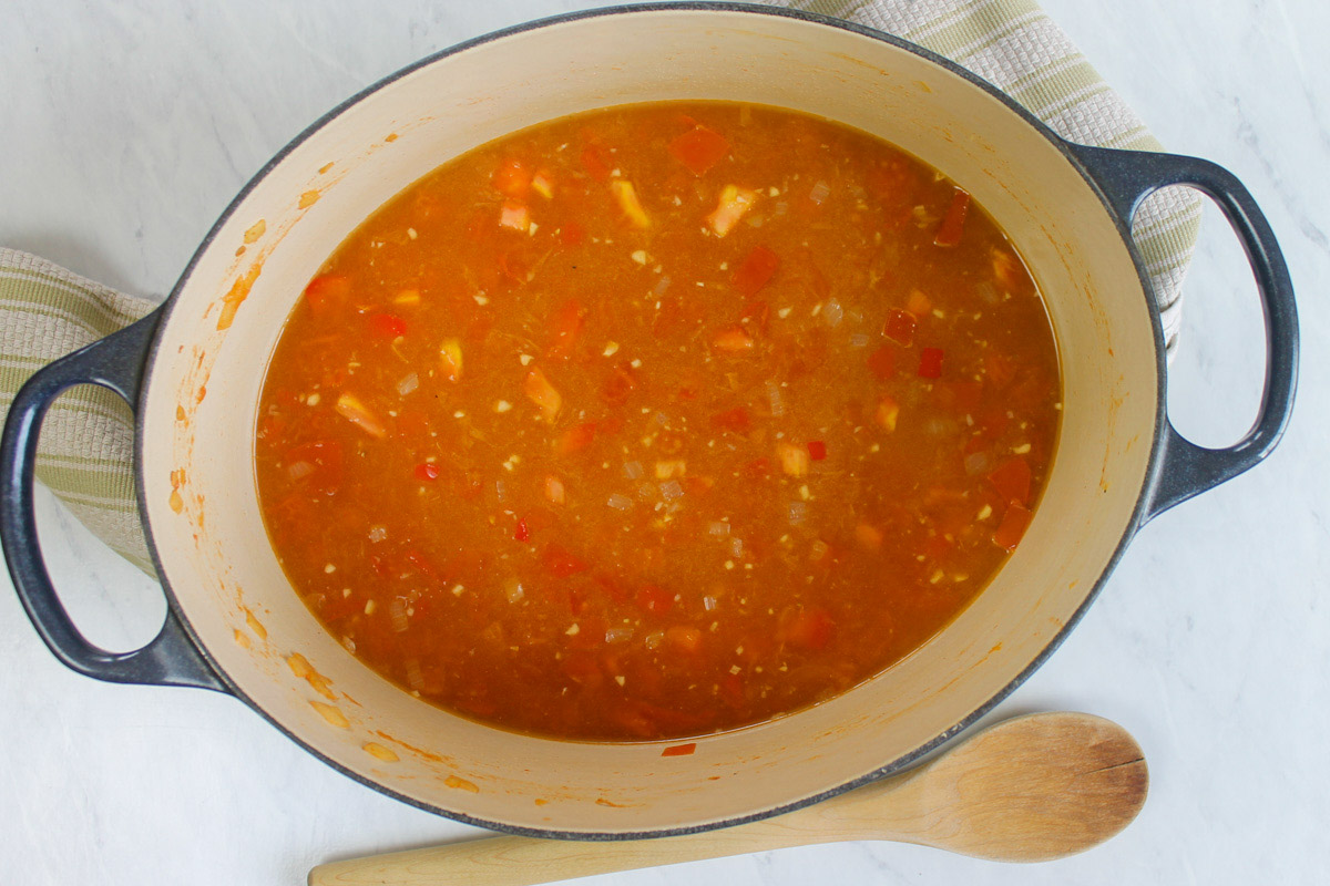 Adding Chicken stock and rice to simmer with the vegetables.