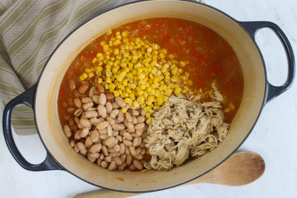 Adding beans, corn and chicken to the simmering stock.
