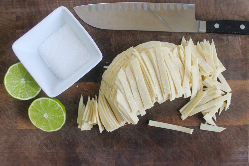 Making homemade salty lime corn tortilla strips.
