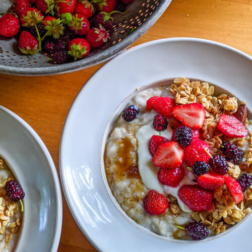 A bowl of creamy steel cut oats with berries and granola.