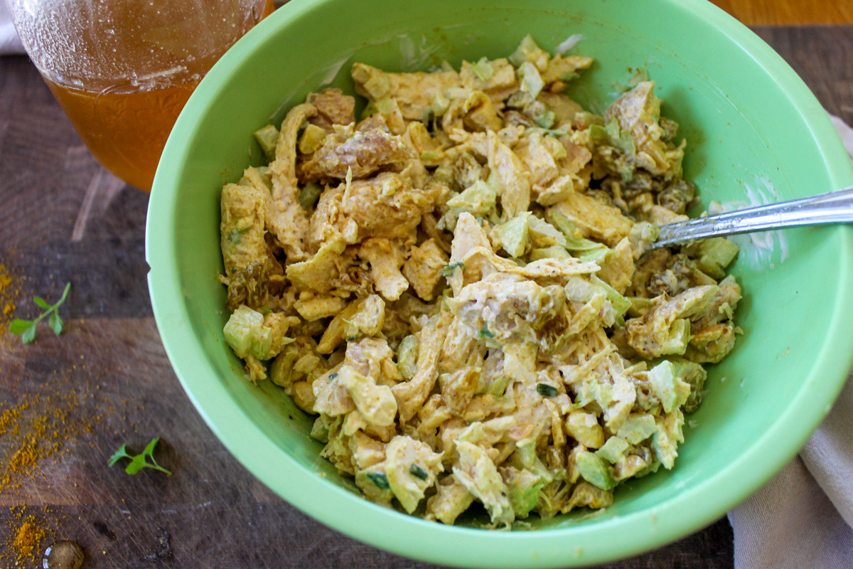 Bowl of curry chicken salad ingredients being mixed with mayo.