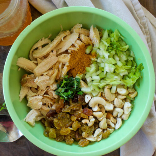 A bowl of curry chicken salad ingredients ready to be mixed.