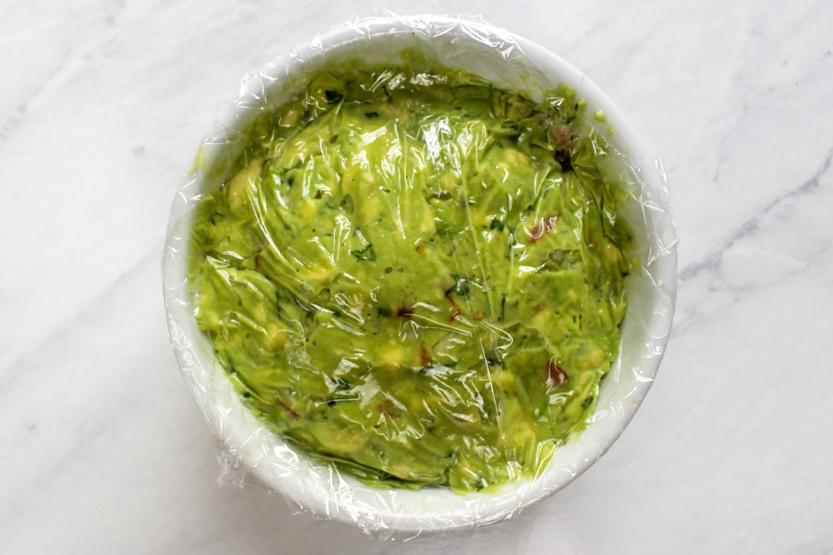 Guacamole storage wrapping a bowl in plastic wrap.