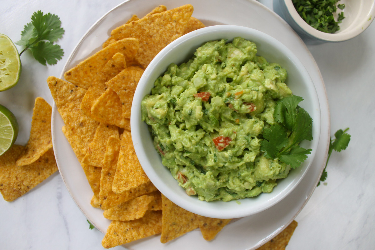 A bowl of Guacamole with tortilla chips.