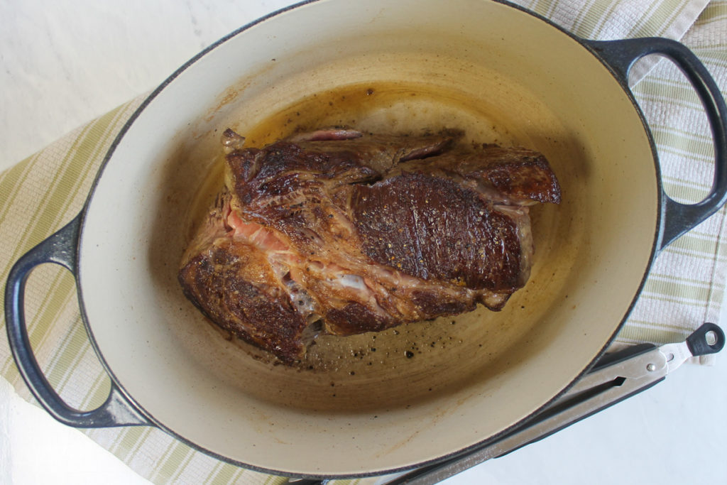Searing beef roast in a Dutch oven until browned.