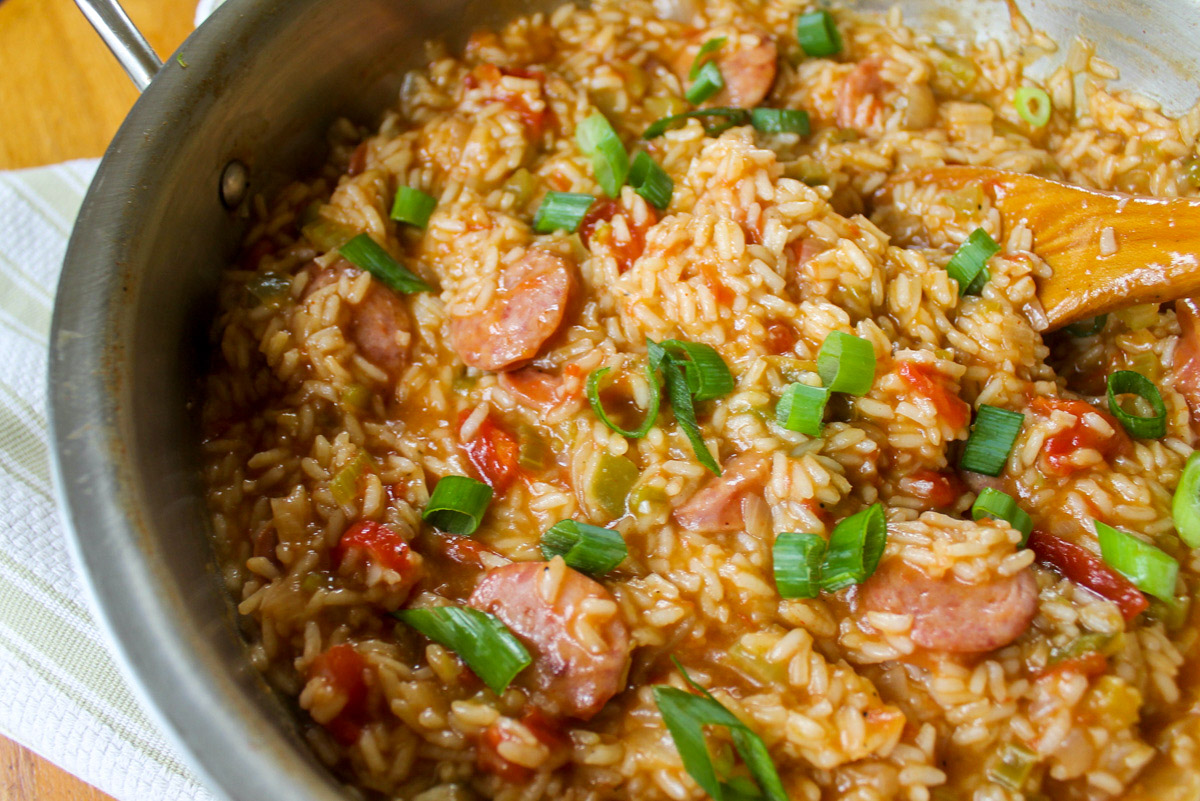 One pot creamy jambalaya in a skillet with a wooden spoon.