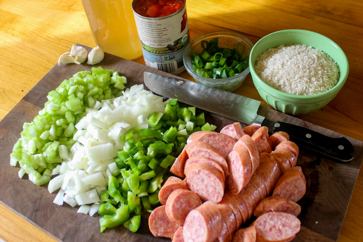 Prepped jambalaya ingredients on a cutting board including chopped veggies and sausage.