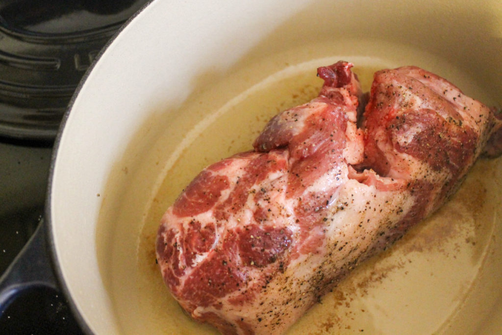 Searing a pork roast in a Dutch oven.