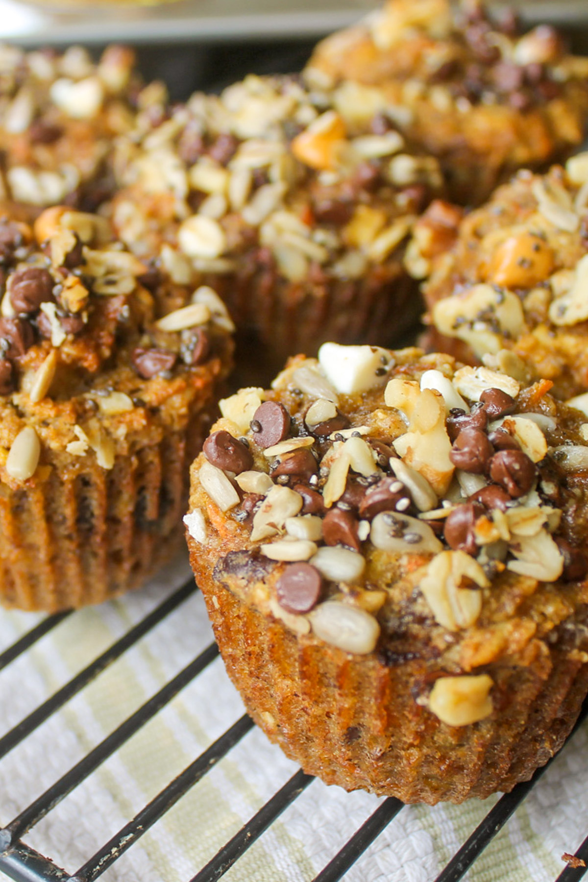 Morning Glory Banana Carrot Muffins on a wire rack with seed and nut chocolate chip topping.