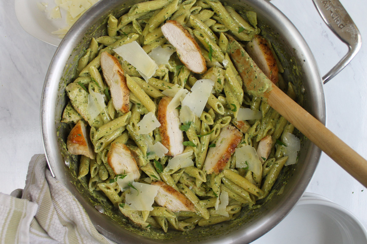 Pesto Alfredo Pasta with Chicken in a skillet with a wooden spoon.
