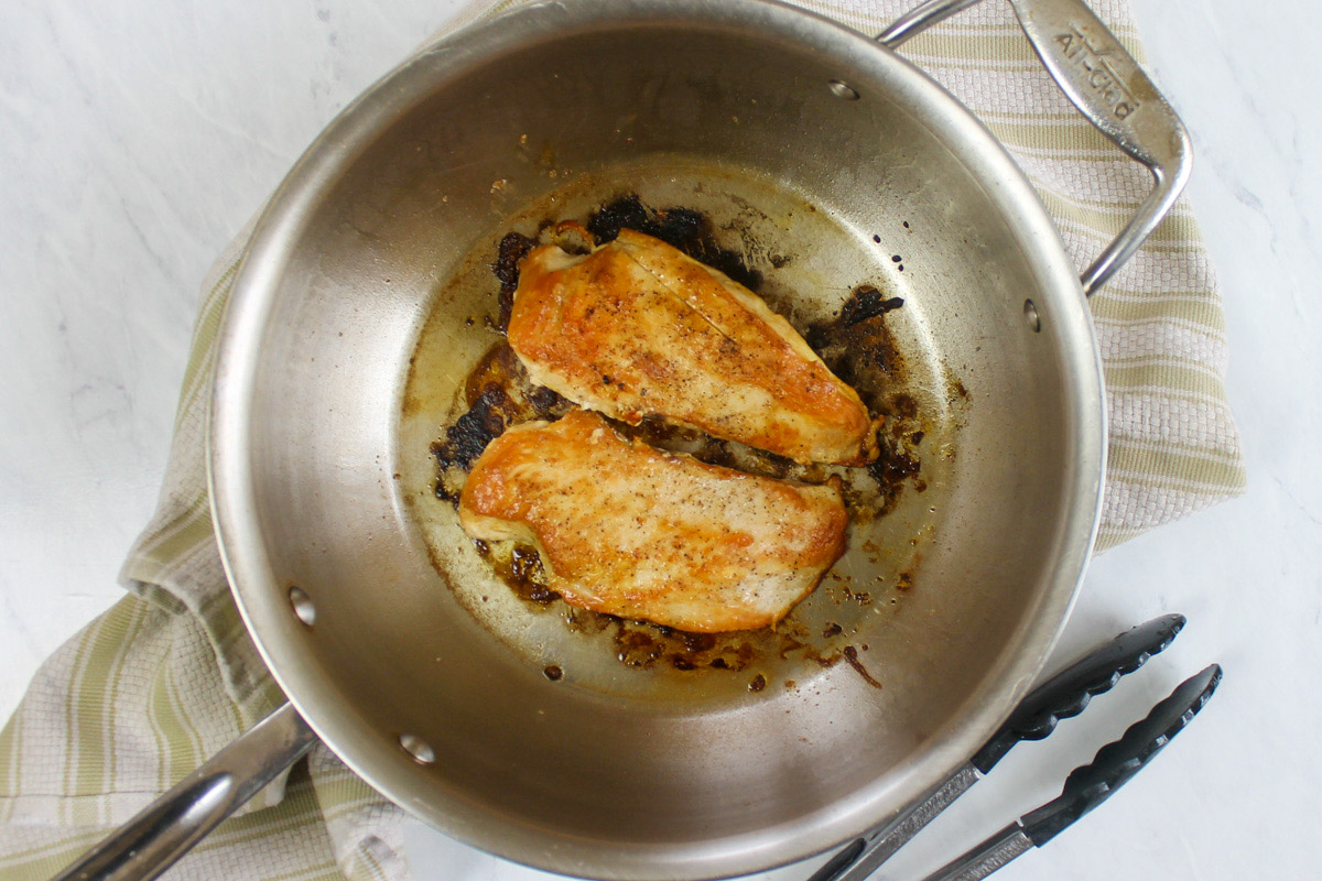 Pan fried chicken breasts in a skillet.