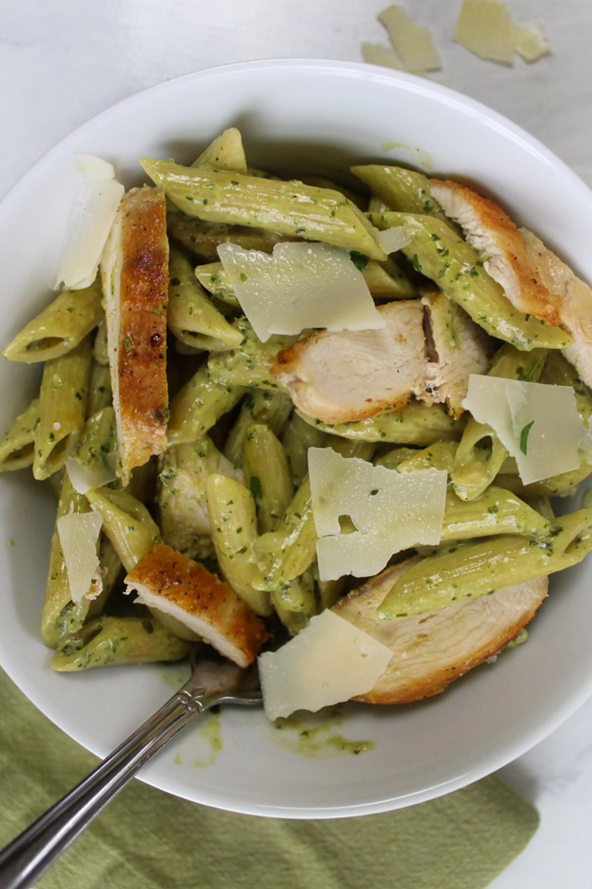 A white bowl of Pesto Alfredo Pasta with sliced chicken.