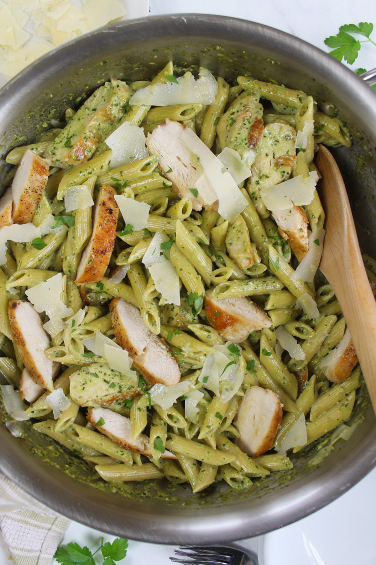 A skillet of the finished Pesto Alfredo Pasta with sliced chicken and Parmesan cheese.