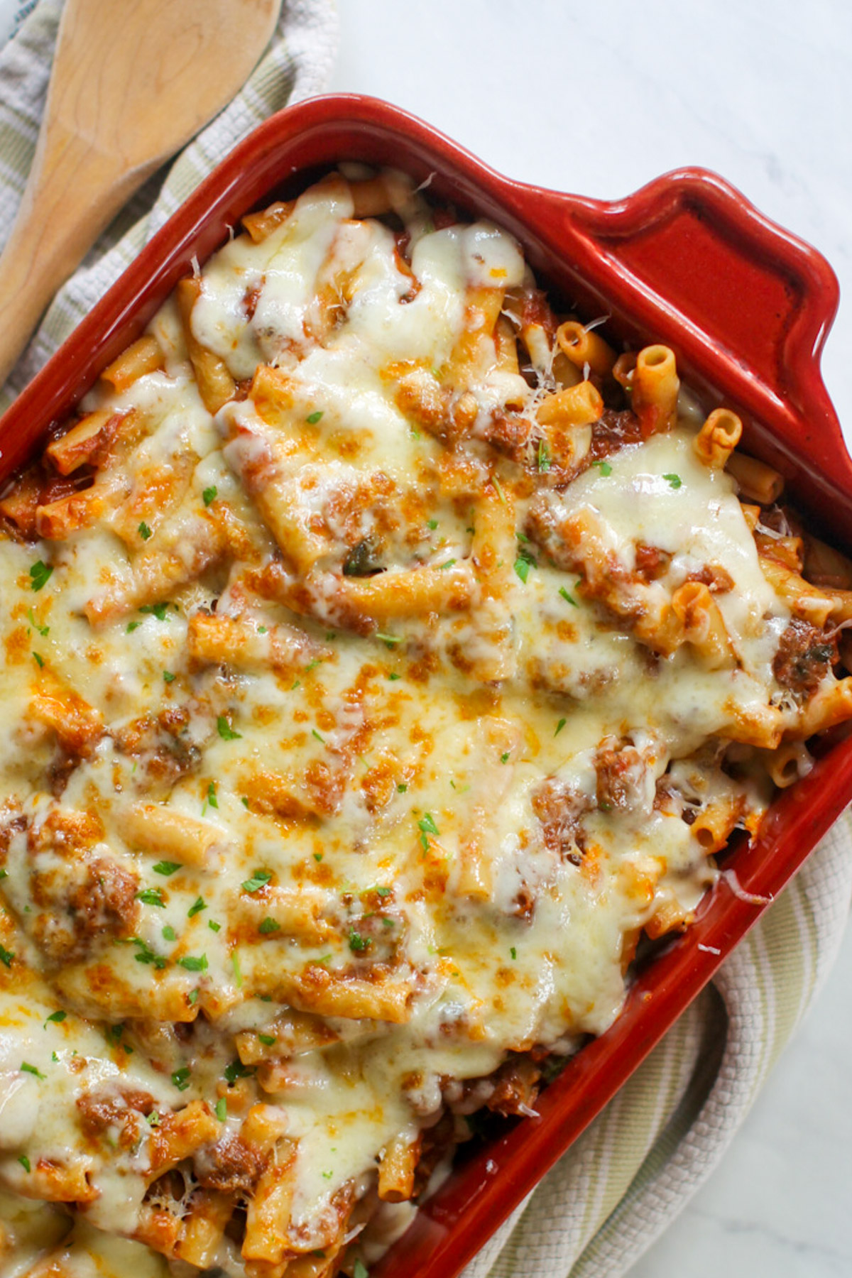 Ragu Pasta Bake in a red casserole dish covered with melty cheese.