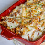 A red baking dish of melted cheesy pasta in leftover shredded beef ragu sauce.