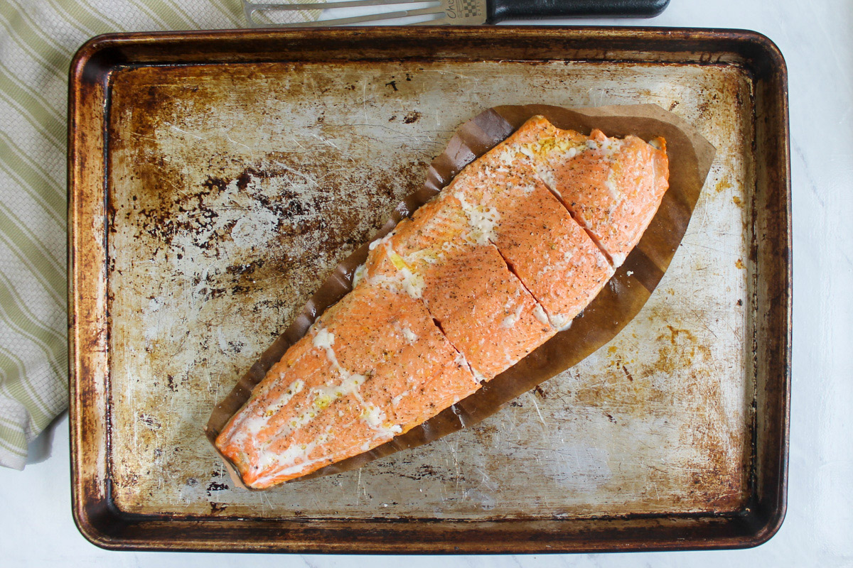 A filet of wild caught salmon roasted on a sheet pan with a trimmed brown paper bag under it to prevent it from sticking.