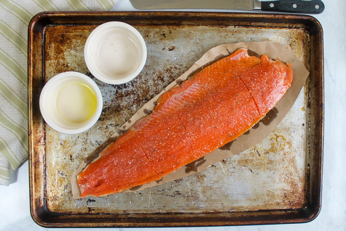 A raw filet of Wild Caught Salmon ready to be roasted on a sheet pan with olive oil, salt and pepper.