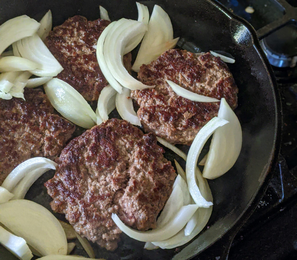 Cast Iron Skillet Burgers searing with onions