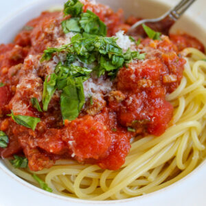 Spaghetti and meat sauce topped with chopped basil.