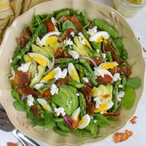 A platter of asparagus salad with crispy prosciutto, goat cheese, and hard boiled eggs.