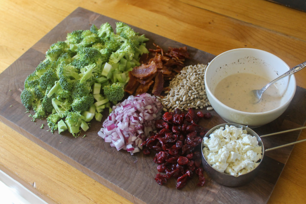 Broccoli Salad ingredients on a cutting board with no mayo dressing.