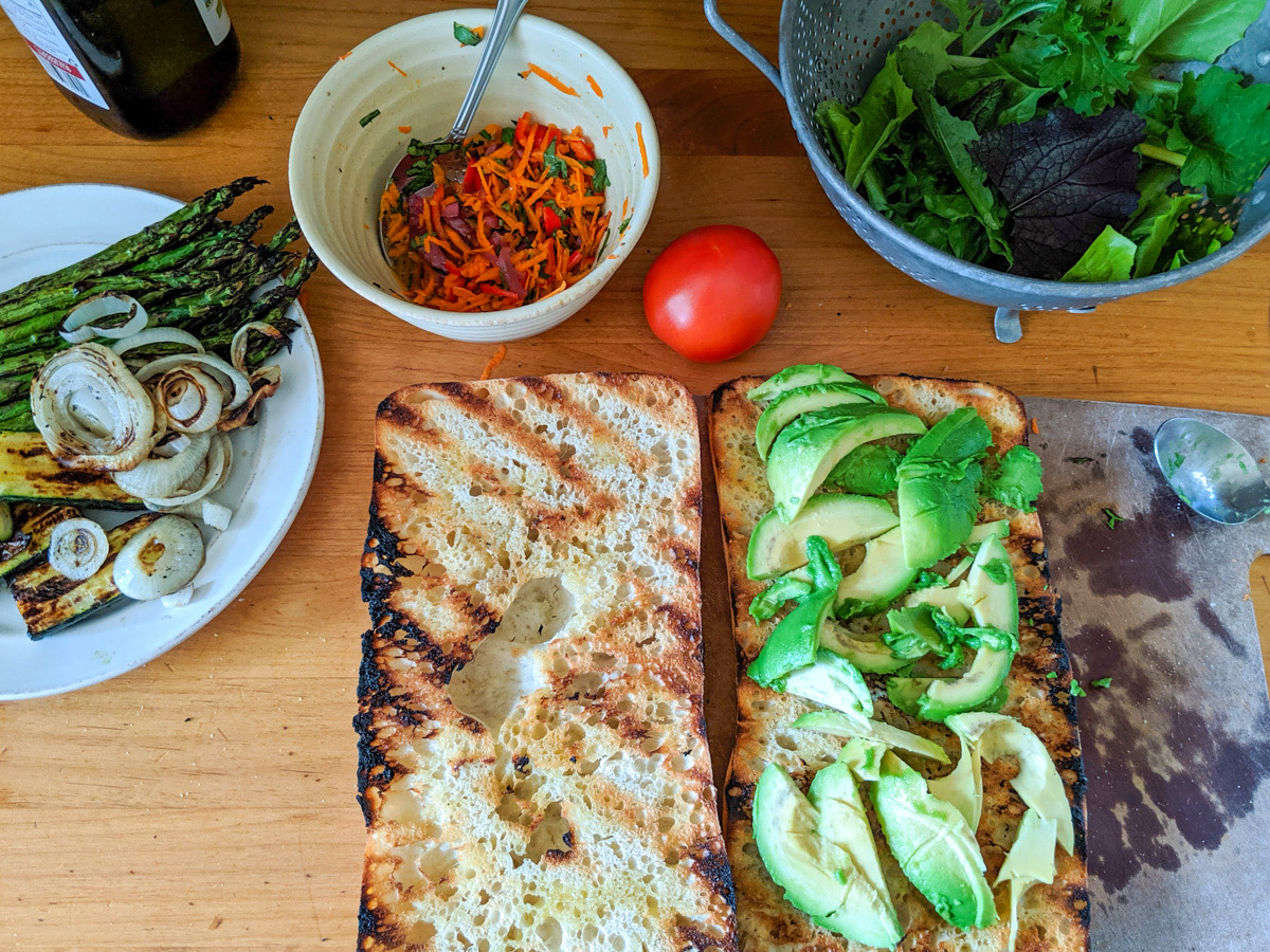 Grilled ciabatta topped with avocado, ready to build the sub sandwich.