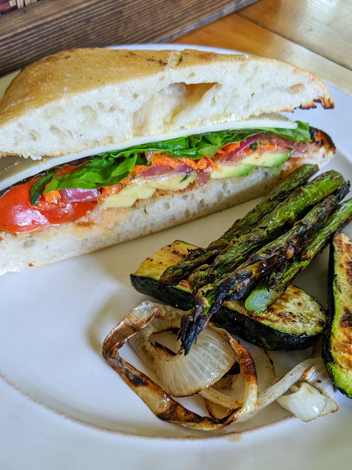 A sandwich wedge of Italian Sub with giardiniera on a plate with grilled veggies.
