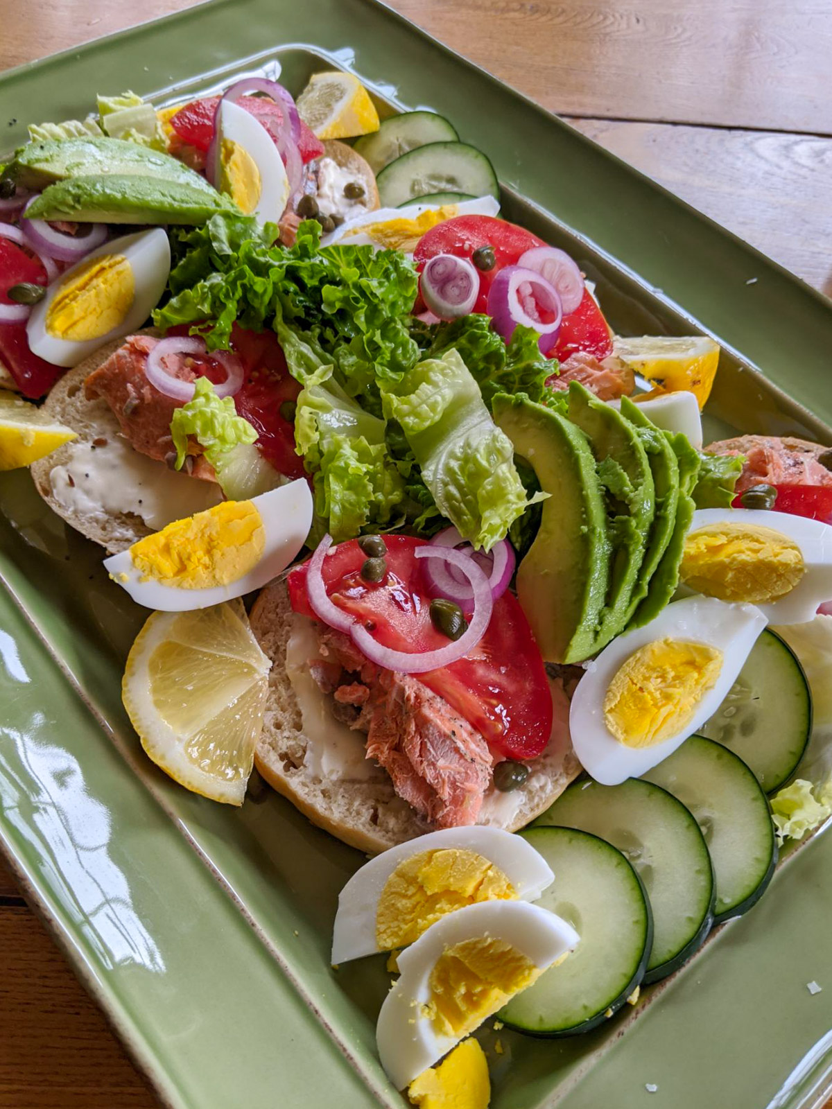 Salmon avocado bagel platter for dinner with hard boiled eggs, cucumber and capers.