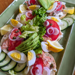 Plater of Salmon Avocado Bagels with hard boiled eggs, tomato and cucumber.