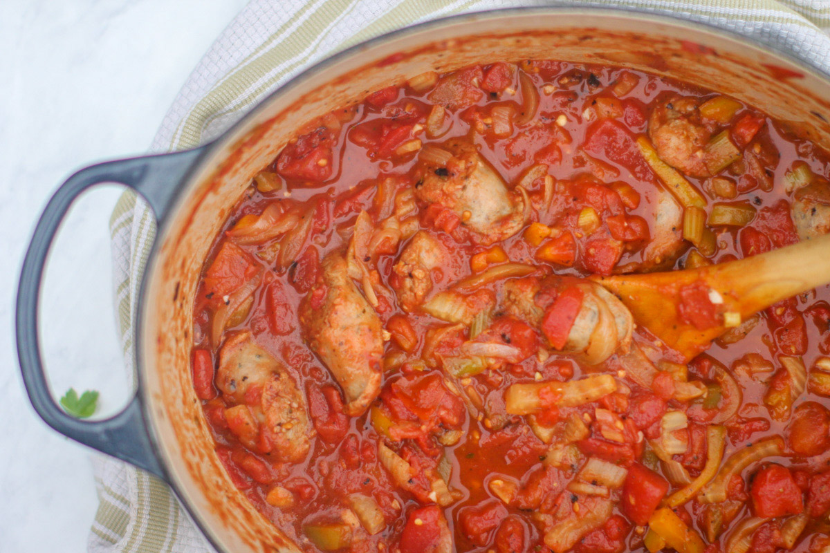 A large pot of chunky tomato sauce with sausage, peppers, onions, and fennel.